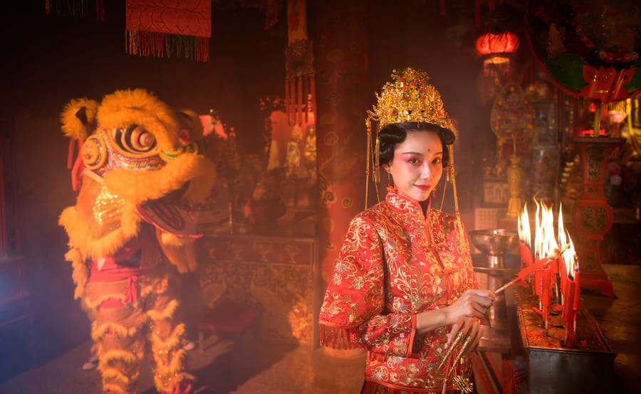 Mujer china prendiendo las velas por año nuevo chino con dragón de fondo